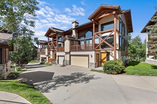 2743 Timber Ct Unit 3, Steamboat Springs, CO 80487 - view of front facade featuring driveway, a balcony, a garage, a chimney, and stone siding