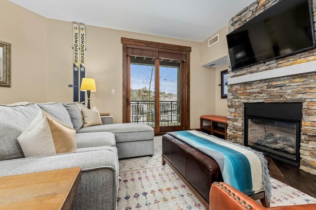 living area with a fireplace, wood finished floors, and visible vents