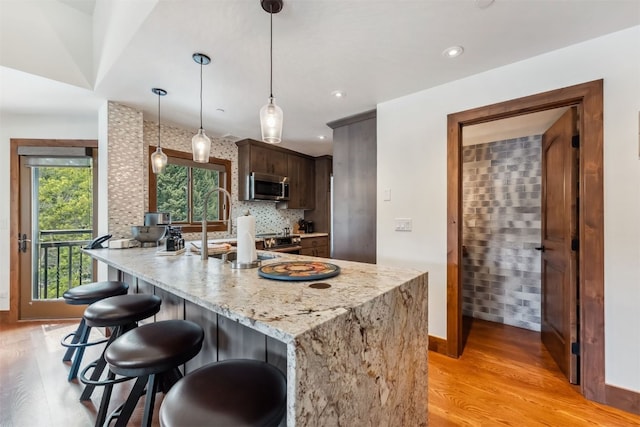 405 Village Rd Unit 405, Breckenridge, CO 80424 - kitchen featuring stainless steel microwave, light wood-style floors, a kitchen breakfast bar, a peninsula, and decorative light fixtures