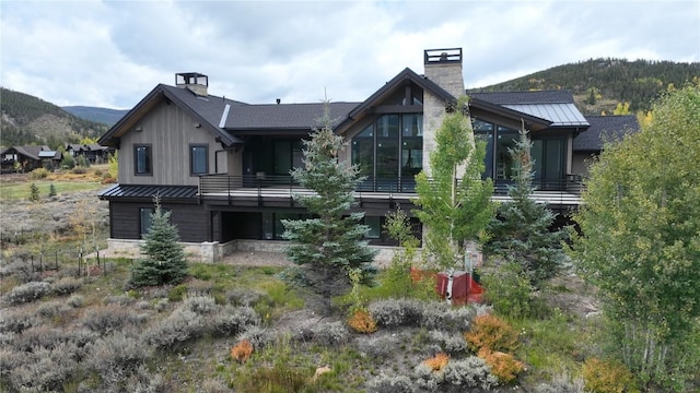 rear view of house with a standing seam roof, a chimney, a mountain view, and metal roof