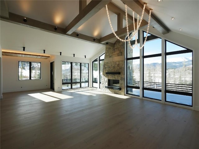 unfurnished living room with high vaulted ceiling, wood finished floors, a stone fireplace, and beamed ceiling