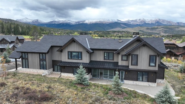 view of front facade featuring stone siding, a standing seam roof, roof with shingles, and a mountain view