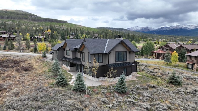 exterior space featuring board and batten siding, a standing seam roof, stone siding, a mountain view, and metal roof