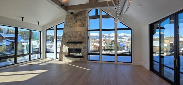 unfurnished living room featuring high vaulted ceiling, wood finished floors, a mountain view, and a fireplace