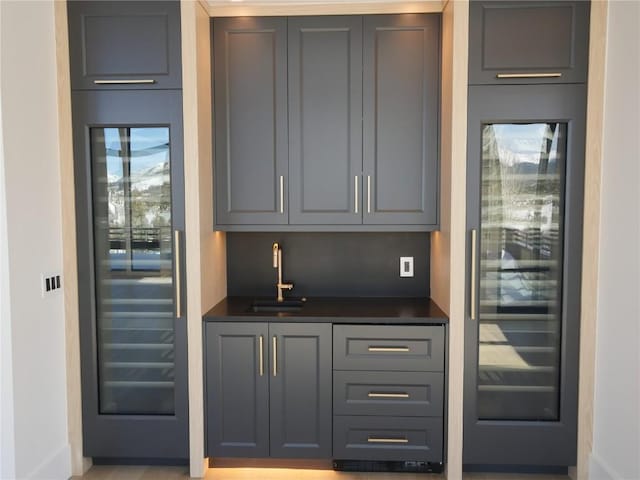 bar featuring beverage cooler, baseboards, a sink, and wet bar