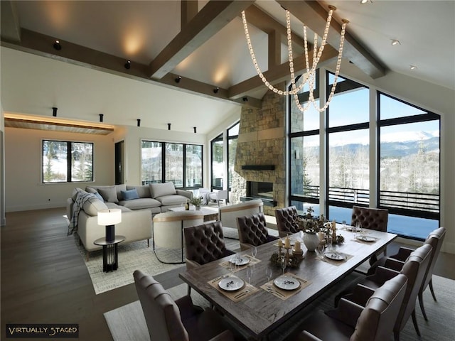 dining room featuring a stone fireplace, a wealth of natural light, wood finished floors, and beam ceiling