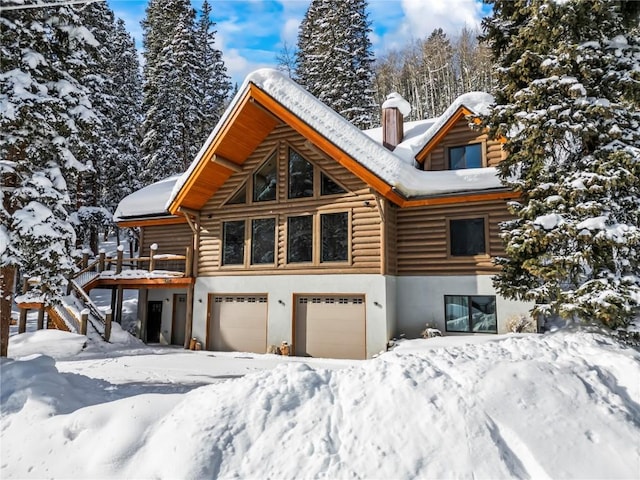 view of front of home featuring log exterior, an attached garage, a chimney, and stucco siding