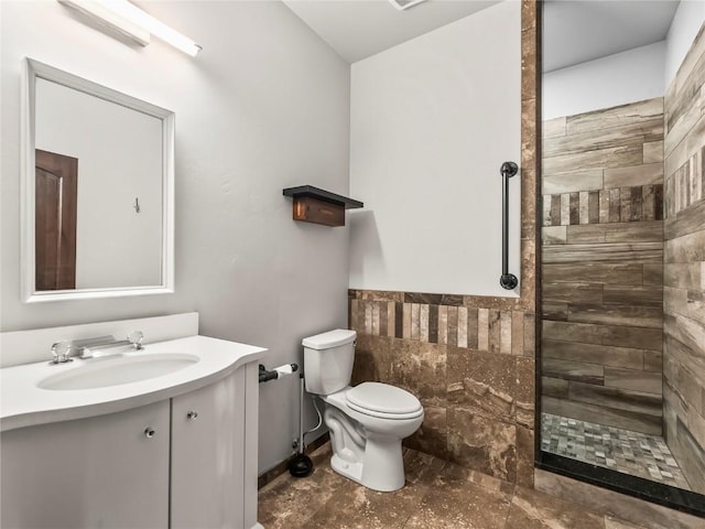 full bath with toilet, vanity, tile walls, wainscoting, and walk in shower