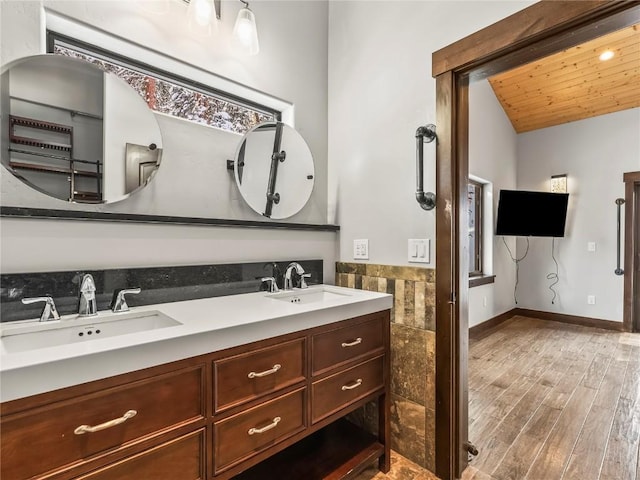full bath with vaulted ceiling, wood finished floors, a sink, and double vanity