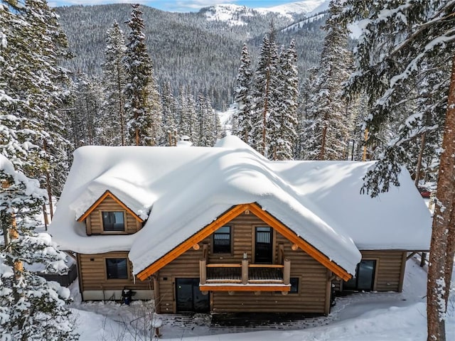 exterior space featuring faux log siding, a forest view, and a mountain view