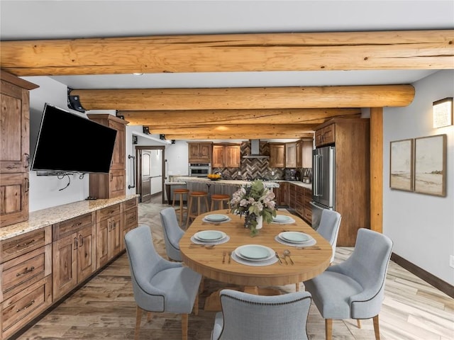 dining room with light wood finished floors, baseboards, and beam ceiling