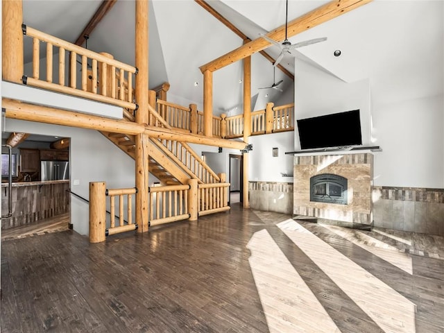 unfurnished living room featuring beamed ceiling, wood finished floors, high vaulted ceiling, and a fireplace with raised hearth
