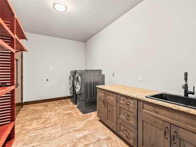 laundry room featuring a sink, baseboards, stone finish flooring, cabinet space, and washer and dryer