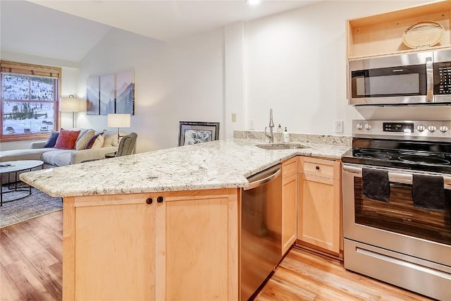140 Ida Belle Dr Unit 8294, Dillon, CO 80435 - kitchen with appliances with stainless steel finishes, light brown cabinetry, light wood-style flooring, a peninsula, and light stone countertops