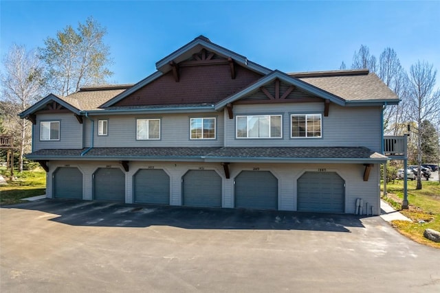 view of front of house featuring a garage, aphalt driveway, and a shingled roof