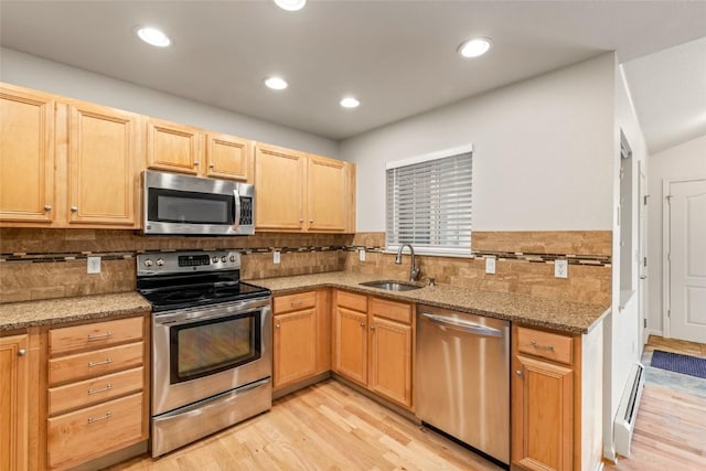kitchen featuring light stone counters, stainless steel appliances, light wood-style flooring, and a sink