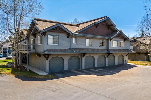 view of front facade with driveway, a shingled roof, and an attached garage
