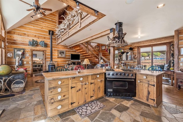 76 County Road 60b, Maybell, CO 81640 - kitchen with gas range, open floor plan, a wood stove, a ceiling fan, and a high ceiling
