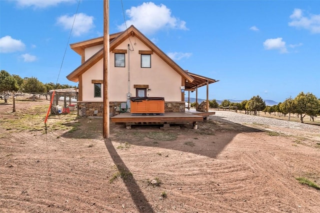 76 County Road 60b, Maybell, CO 81640 - rear view of house with a hot tub, stone siding, and stucco siding