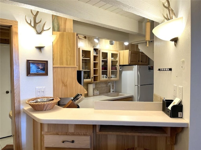 1920 Ski Time Square Dr Unit 208, Steamboat Springs, CO 80487 - kitchen featuring freestanding refrigerator, glass insert cabinets, light countertops, and a peninsula