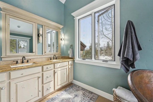 bathroom with a sink, baseboards, and double vanity