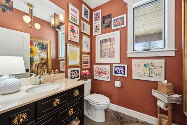 bathroom with baseboards, a wealth of natural light, toilet, and vanity