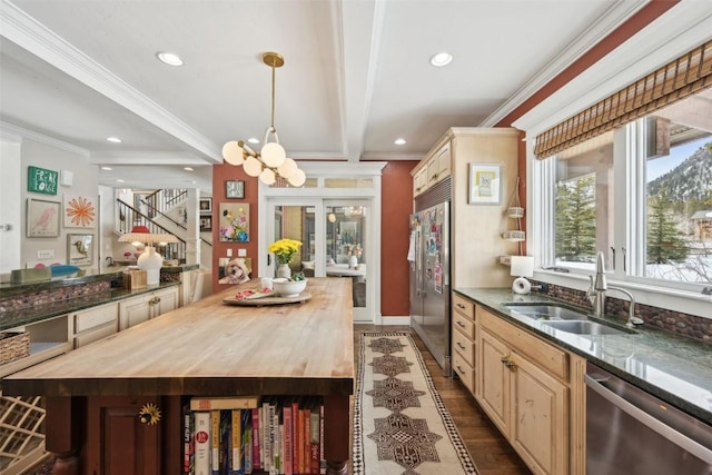kitchen with butcher block countertops, a sink, appliances with stainless steel finishes, and ornamental molding