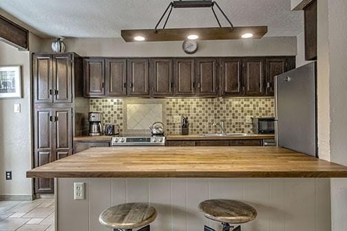820 Columbine Rd Unit 10, Breckenridge, CO 80424 - kitchen featuring wood counters, dark brown cabinets, and stainless steel appliances