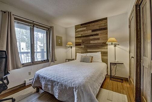 820 Columbine Rd Unit 10, Breckenridge, CO 80424 - bedroom with baseboards, wood walls, wood finished floors, and a baseboard heating unit