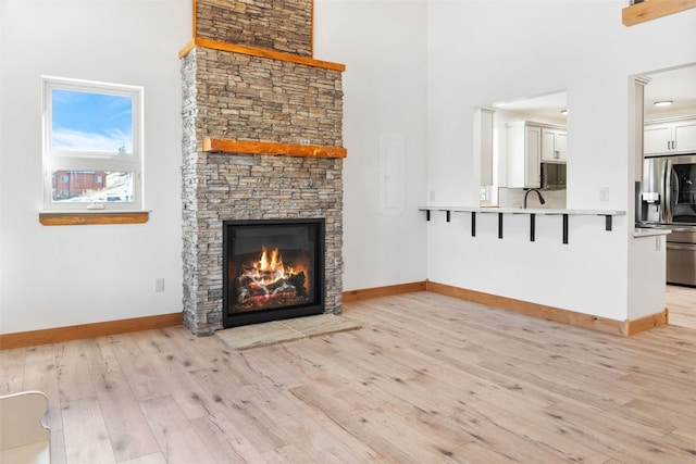 3415 Redhill Rd, Fairplay, CO 80440 - unfurnished living room featuring a high ceiling, light wood-type flooring, baseboards, and a fireplace