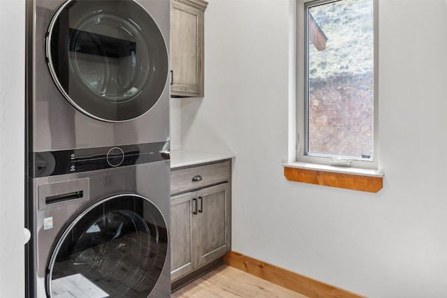 3415 Redhill Rd, Fairplay, CO 80440 - laundry room with cabinet space, stacked washing machine and dryer, light wood-style flooring, and baseboards