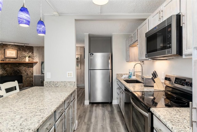 72 Corinthian Cir Unit 102, Dillon, CO 80435 - kitchen featuring stainless steel appliances, a sink, a textured ceiling, wood finished floors, and light stone countertops