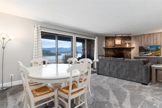 72 Corinthian Cir Unit 102, Dillon, CO 80435 - carpeted dining area featuring a textured ceiling, a stone fireplace, wood walls, and baseboards