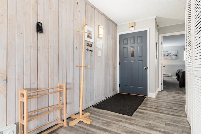 72 Corinthian Cir Unit 102, Dillon, CO 80435 - entryway with wooden walls, wood finished floors, crown molding, baseboards, and a baseboard heating unit