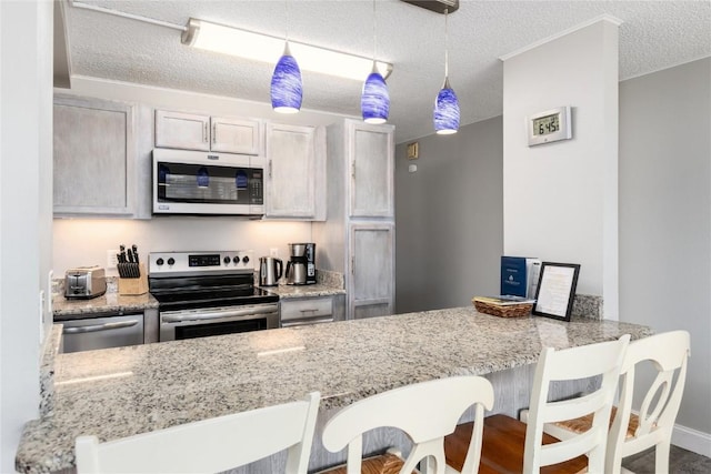 72 Corinthian Cir Unit 102, Dillon, CO 80435 - kitchen with appliances with stainless steel finishes, a textured ceiling, a peninsula, light stone counters, and a kitchen bar