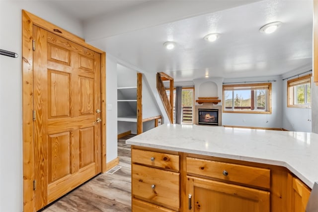 80 Cove Blvd Unit 103, Dillon, CO 80435 - kitchen with light wood-style flooring, a glass covered fireplace, open floor plan, light stone countertops, and baseboards
