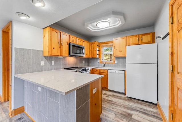 80 Cove Blvd Unit 103, Dillon, CO 80435 - kitchen with stainless steel appliances, a sink, a peninsula, light wood-style flooring, and tasteful backsplash