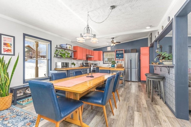 dining room with vaulted ceiling, ornamental molding, light hardwood / wood-style floors, and a textured ceiling