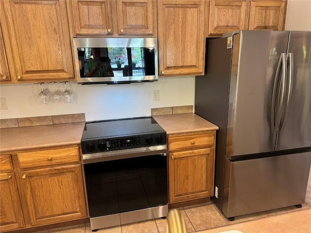 951 Lakepoint Dr Unit C5, Frisco, CO 80443 - kitchen with appliances with stainless steel finishes, brown cabinetry, and light tile patterned flooring