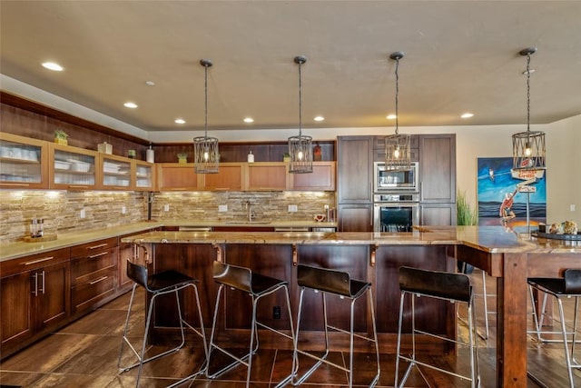 kitchen with stainless steel appliances, glass insert cabinets, a sink, and decorative backsplash