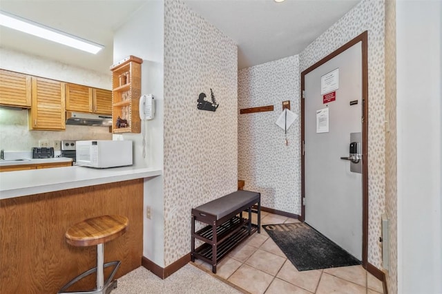 2015 Walton Creek Rd Unit 114, Steamboat Springs, CO 80487 - kitchen with under cabinet range hood, wallpapered walls, baseboards, and white microwave