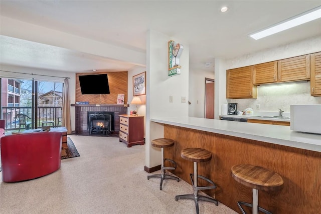 2015 Walton Creek Rd Unit 114, Steamboat Springs, CO 80487 - kitchen featuring light colored carpet, a brick fireplace, light countertops, open floor plan, and a breakfast bar