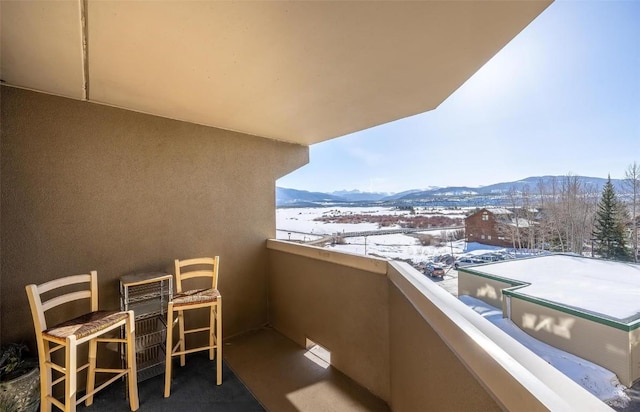 snow covered back of property with a mountain view