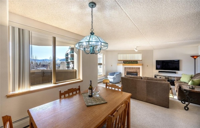 carpeted dining space with a baseboard radiator, a tile fireplace, a textured ceiling, and an inviting chandelier
