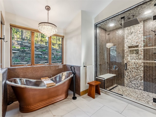 59 Mountain Bluebell Rd, Keystone, CO 80435 - full bathroom with marble look tiles, a shower stall, a soaking tub, and a chandelier