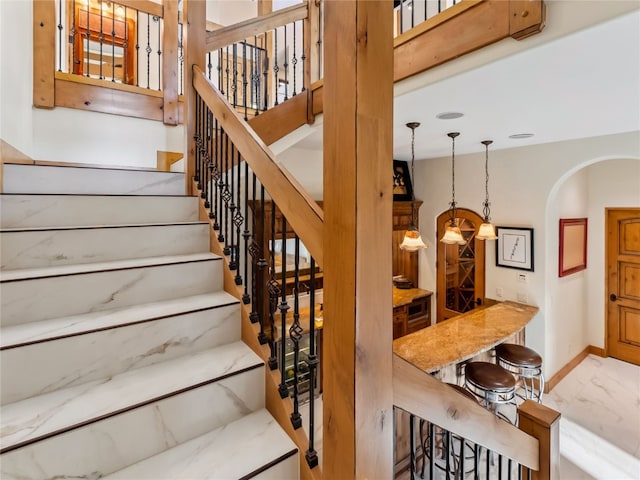 59 Mountain Bluebell Rd, Keystone, CO 80435 - staircase featuring marble look tile flooring, baseboards, and arched walkways