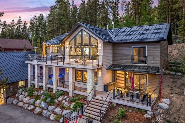 456 Forest Hills Dr, Breckenridge, CO 80424 - back of house at dusk with a balcony, a standing seam roof, a metal roof, stairway, and view of scattered trees