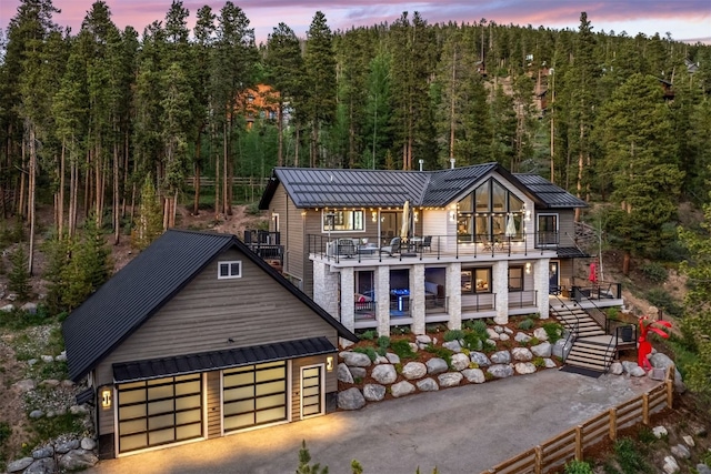 456 Forest Hills Dr, Breckenridge, CO 80424 - back of house at dusk with a balcony, a metal roof, a wooded view, and a standing seam roof