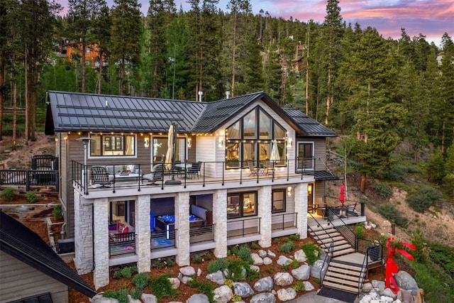 456 Forest Hills Dr, Breckenridge, CO 80424 - back of house at dusk with a standing seam roof, a balcony, stairs, a metal roof, and a view of trees