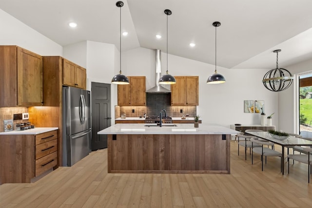 30350 Hostler Dr, Oak Creek, CO 80467 - kitchen with freestanding refrigerator, wall chimney exhaust hood, brown cabinetry, and lofted ceiling